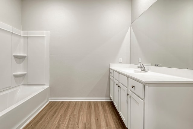 bathroom featuring wood finished floors, vanity, tub / shower combination, and baseboards