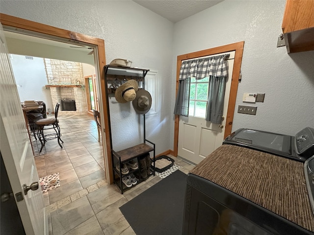 15395 Kitty Hawk Dr, Waller, TX 77484 - washroom with washer / dryer, a textured wall, light tile patterned flooring, and a fireplace