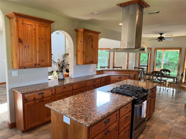 15395 Kitty Hawk Dr, Waller, TX 77484 - kitchen with stainless steel range with gas cooktop, visible vents, brown cabinetry, and island range hood