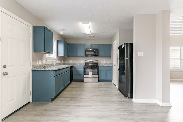 kitchen with blue cabinets, a sink, light wood-type flooring, baseboards, and black appliances