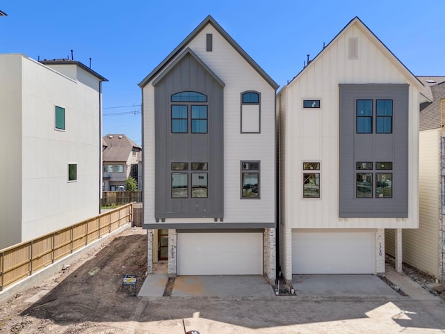 townhome / multi-family property with driveway, a garage, board and batten siding, and fence