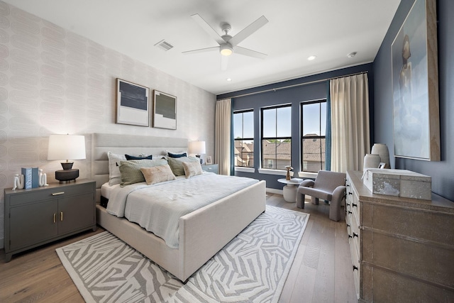 bedroom with recessed lighting, visible vents, wallpapered walls, and wood finished floors