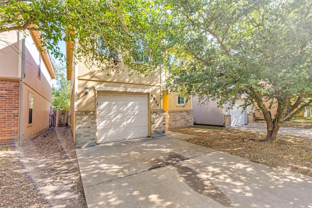 4934 S Cancun Dr, Houston, TX 77045 - view of property hidden behind natural elements with a garage, stucco siding, and concrete driveway