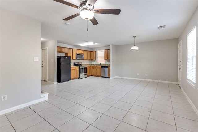 4934 S Cancun Dr, Houston, TX 77045 - kitchen featuring light tile patterned flooring, ceiling fan, a healthy amount of sunlight, and stainless steel appliances