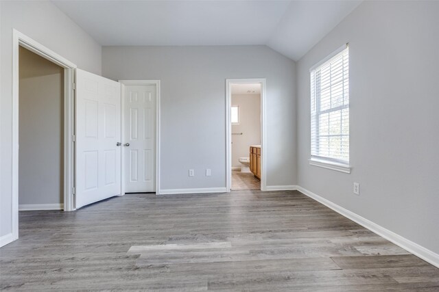 4934 S Cancun Dr, Houston, TX 77045 - unfurnished bedroom with vaulted ceiling, wood finished floors, multiple windows, and ensuite bathroom