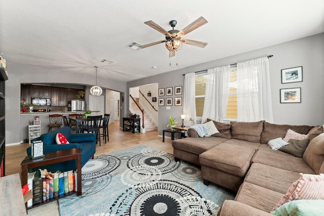 living room with a ceiling fan, stairs, visible vents, and light tile patterned floors