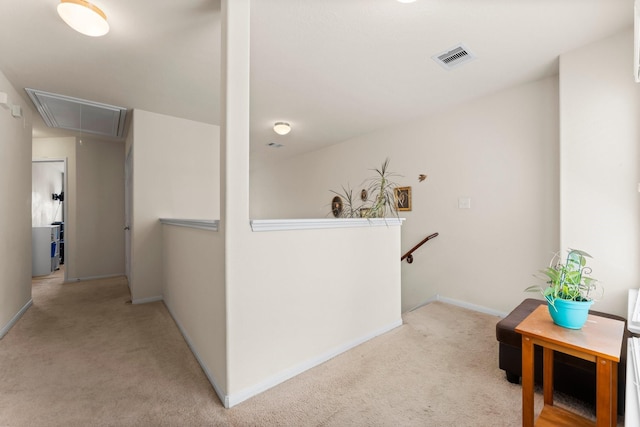 hall with attic access, carpet, baseboards, and an upstairs landing