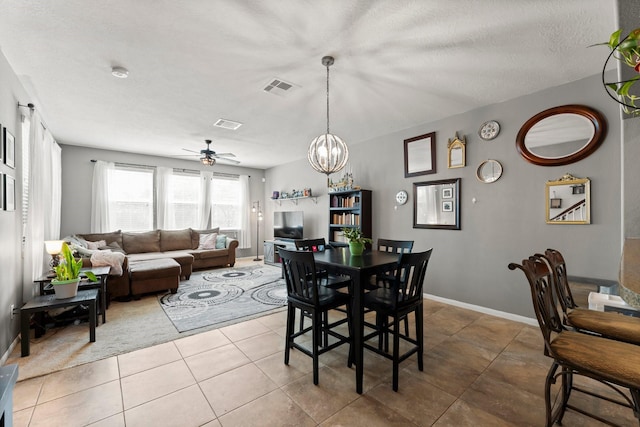 tiled dining room with ceiling fan with notable chandelier, baseboards, visible vents, and a textured ceiling