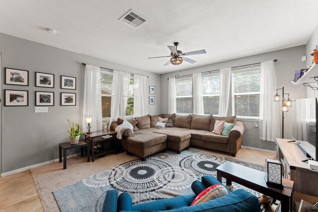 living room with baseboards, a ceiling fan, and visible vents
