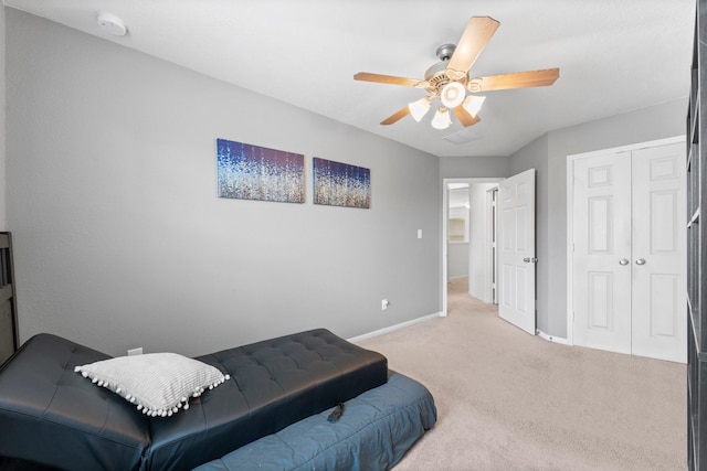 bedroom featuring light colored carpet, baseboards, a ceiling fan, and a closet