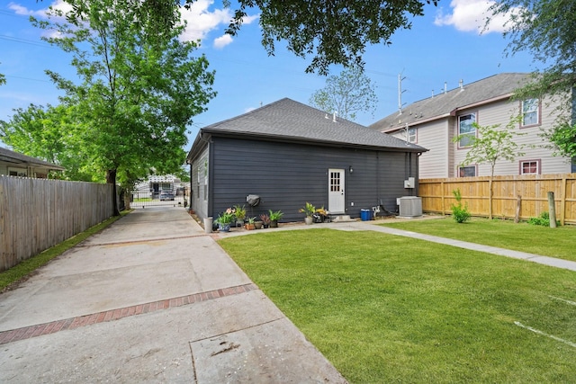 rear view of house featuring driveway, fence, and a yard