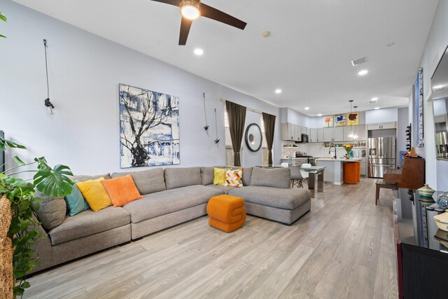 living room with light wood-style flooring, visible vents, recessed lighting, and a ceiling fan