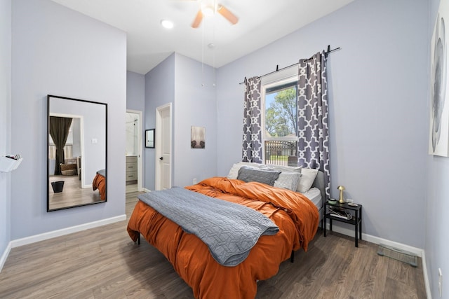 bedroom featuring wood finished floors, visible vents, a ceiling fan, ensuite bath, and baseboards