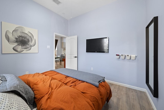 bedroom featuring wood finished floors, visible vents, and baseboards