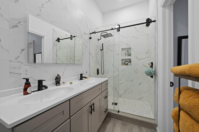 full bathroom featuring double vanity, a marble finish shower, and a sink