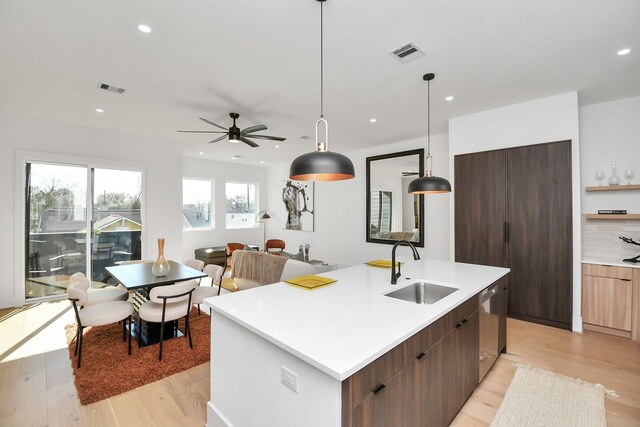 kitchen with a sink, a center island with sink, visible vents, modern cabinets, and dishwasher