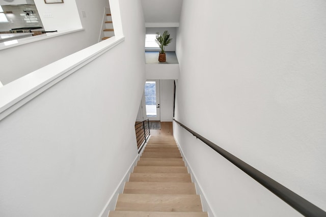 staircase with a high ceiling, wood finished floors, and baseboards