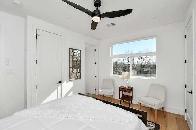 bedroom featuring wood finished floors, visible vents, a ceiling fan, and baseboards