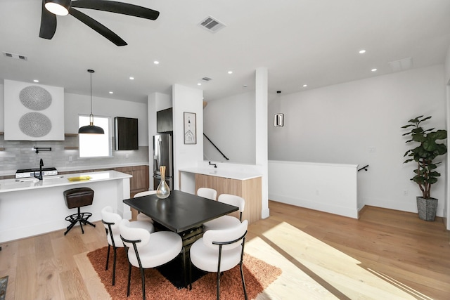 dining area featuring light wood-type flooring, a ceiling fan, and visible vents