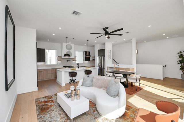 living room with light wood finished floors, visible vents, recessed lighting, and ceiling fan