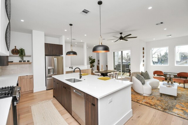 kitchen with a sink, light wood-type flooring, modern cabinets, stainless steel appliances, and visible vents