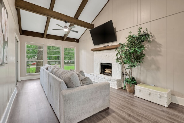 living area with beam ceiling, a ceiling fan, and wood finished floors