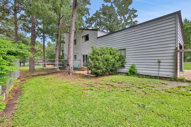 back of property featuring a lawn and fence