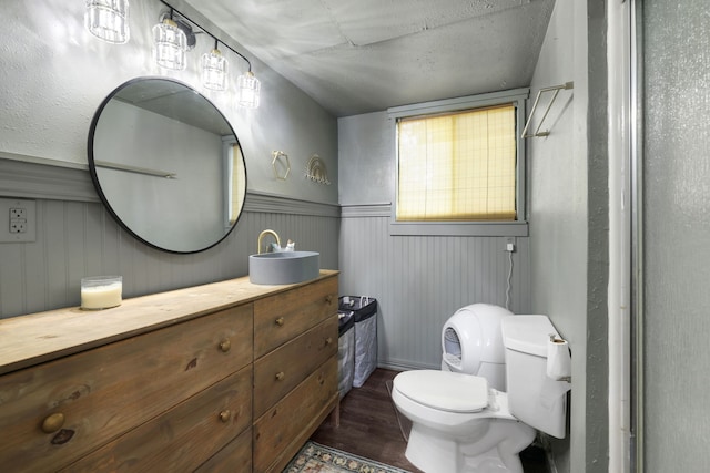 bathroom featuring a wainscoted wall, toilet, wood finished floors, and vanity