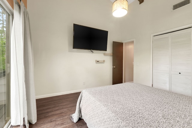 bedroom with dark wood-style flooring, baseboards, visible vents, and a closet