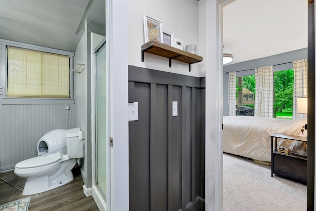 ensuite bathroom featuring ensuite bathroom, wood finished floors, toilet, and a shower stall