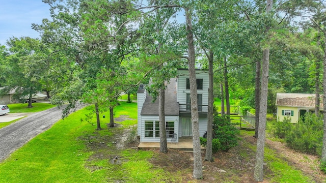 view of front facade featuring a front lawn, a patio area, and a balcony