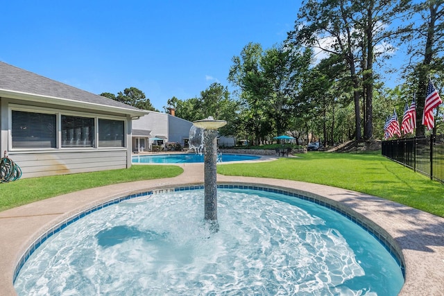 pool with a jacuzzi, fence, and a yard