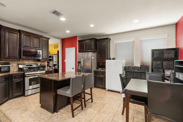 13207 Davenport Hills Ln, Humble, TX 77346 - kitchen with visible vents, dark brown cabinetry, tasteful backsplash, and stainless steel appliances