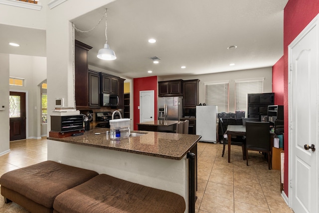 13207 Davenport Hills Ln, Humble, TX 77346 - kitchen featuring dark brown cabinets, appliances with stainless steel finishes, a sink, a peninsula, and light tile patterned floors