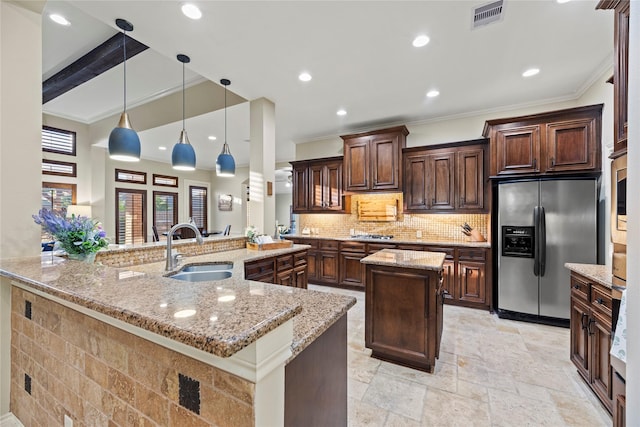 kitchen with crown molding, stainless steel refrigerator with ice dispenser, a sink, and a spacious island