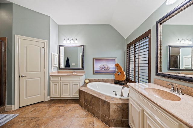 bathroom with a bath, lofted ceiling, stone tile flooring, and a sink