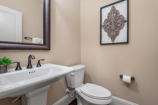 bathroom with toilet, a sink, and baseboards