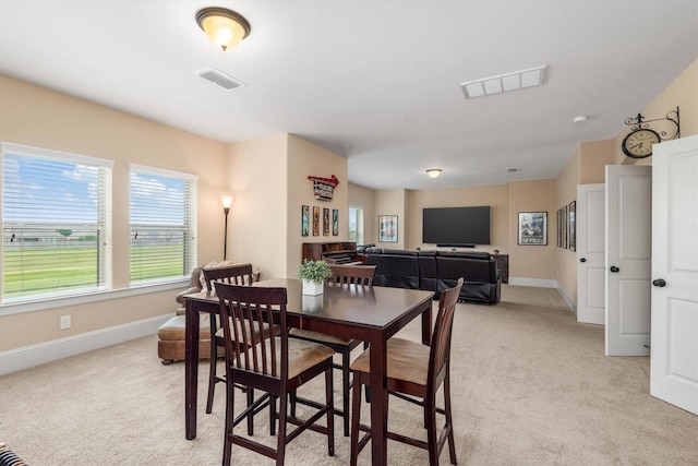 dining space featuring baseboards, visible vents, and light colored carpet