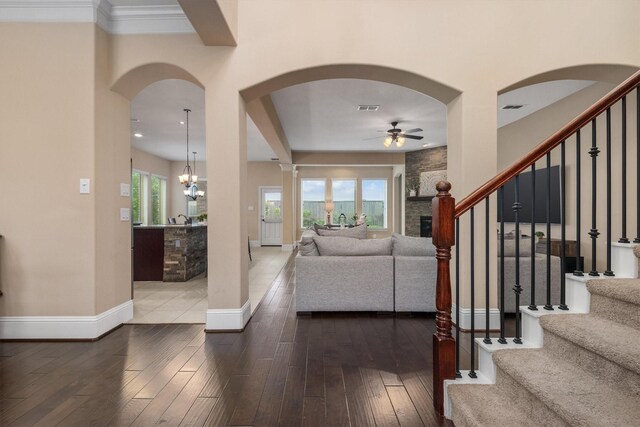 entrance foyer with arched walkways, a ceiling fan, stairs, and visible vents