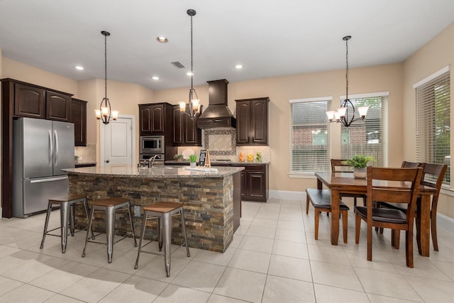 kitchen with stainless steel appliances, tasteful backsplash, dark brown cabinetry, a chandelier, and custom range hood