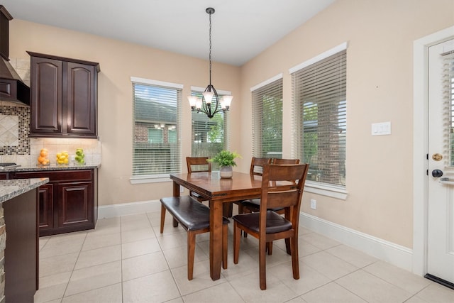 dining space with baseboards, a wealth of natural light, a chandelier, and light tile patterned floors