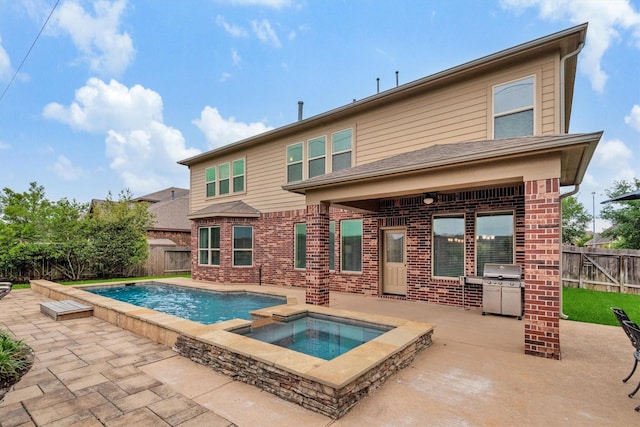 rear view of house with a fenced backyard, brick siding, a patio area, and an in ground hot tub