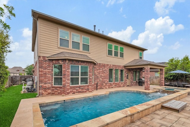 rear view of property featuring a lawn, a fenced backyard, a patio, brick siding, and a pool with connected hot tub