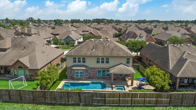 rear view of house featuring a fenced backyard, brick siding, a residential view, and a fenced in pool