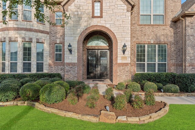 entrance to property featuring brick siding, french doors, and stone siding