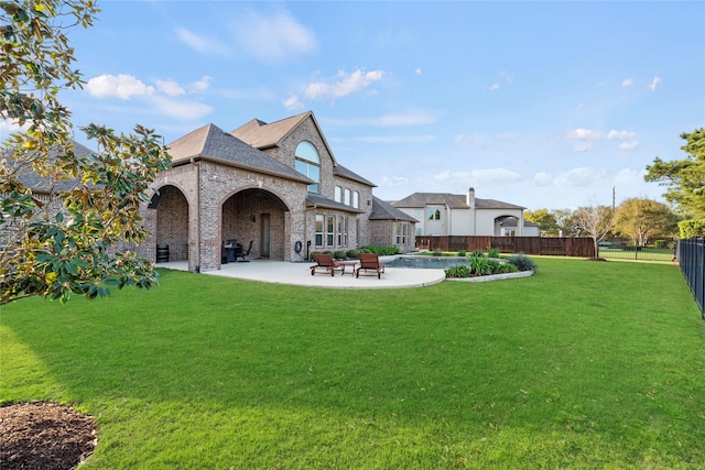 rear view of property featuring a patio area, a shingled roof, fence, a yard, and brick siding