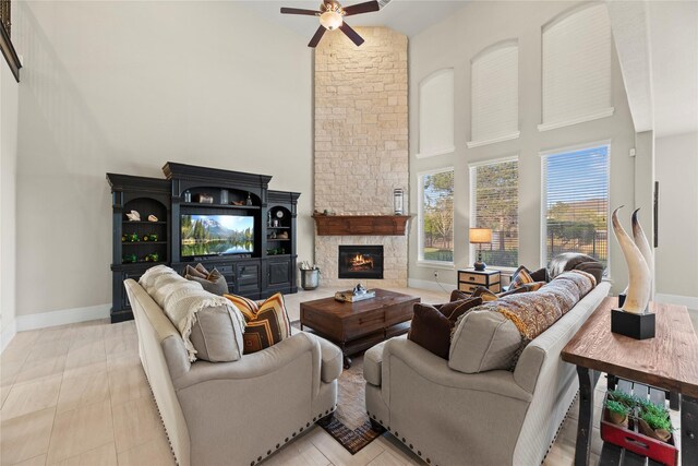 living area featuring baseboards, a high ceiling, a fireplace, and ceiling fan