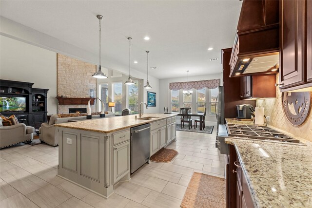 kitchen featuring backsplash, dishwasher, a sink, a center island with sink, and open floor plan