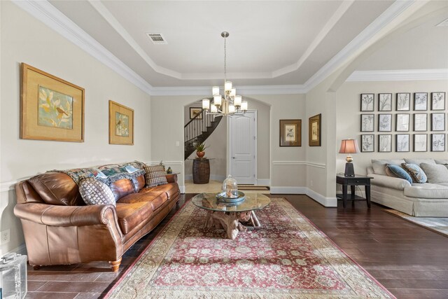 living area with stairway, arched walkways, an inviting chandelier, a raised ceiling, and visible vents