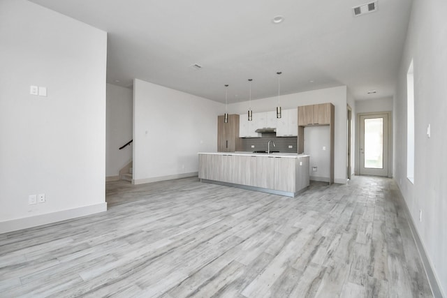 4012 Cusco Ln, Houston, TX 77045 - kitchen with light wood-style flooring, visible vents, backsplash, modern cabinets, and light countertops